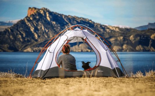 Camping by the lake with a tent and a dog - Gear Up for Adventure: The Best Camping Equipment - The Trailhead Blog - Adventure Travel Gear