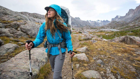 Woman hiking in mountains with trekking poles, Adventure Travel Gear: Your Ultimate Guide to Outdoor Gear, The Trailhead Blog, Adventure Travel Gear.