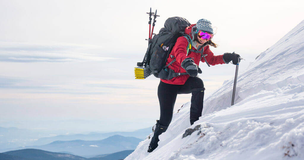 Winter hiker climbing snowy mountain with gear, Gear Up for Winter Hiking: The Trailhead Blog, Adventure Travel Gear.