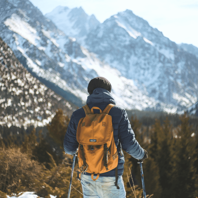 Man with yellow backpack hiking in snowy mountains, Backpacks Collection, Adventure Travel Gear.