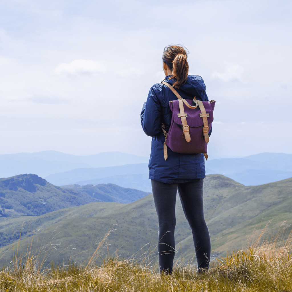 Woman wearing a backpack, enjoying a scenic mountain view during her outdoor adventure. Pants Collection, Adventure Travel Gear